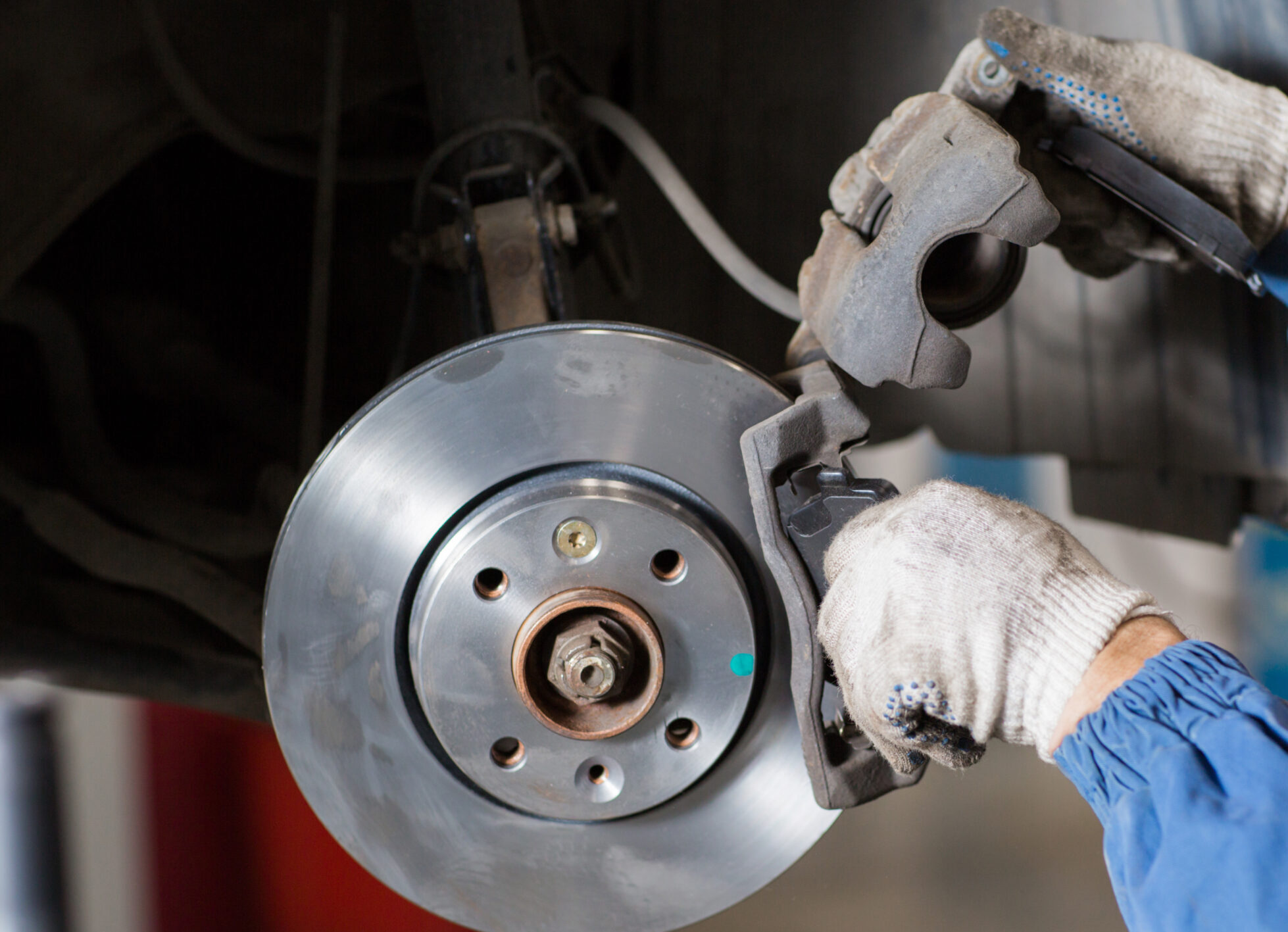 Brand new brake disc on car in a garage. Auto mechanic repairing . Comprehensive Brake Inspections